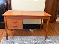 Front view of teak desk showing drawers and legs