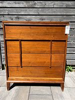 Front view of teak highboy dresser showing drawer layout and overall finish