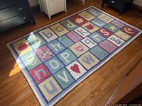 Full view of alphabet rug on wooden floor