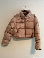 Full view of taupe cropped puffer jacket hanging