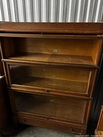 Front view showing bookcase with three glass door sections, crown, and drawer base