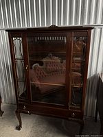 Front view of hardwood china cabinet showing glass door, side mullions, lower drawer, cabriole legs