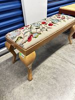 Full view of wooden vanity bench showing needlepoint seat and cabriole legs