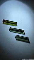 Three baguette-cut green tourmalines on neutral background