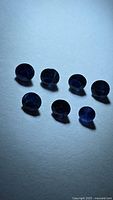 Seven deep blue round sapphires on light background