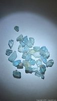 Group of seafoam blue zircon rough crystals under direct light