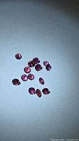 Group of loose round faceted pink-red garnets on light background
