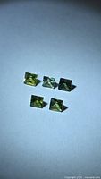 Five square green sapphires on neutral background