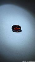 Front view of oval faceted deep red garnet on neutral background