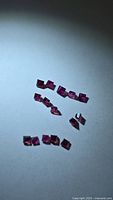 Group of square rubies under light showing colour and cut