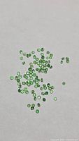 Scattered round green tsavorite garnets on neutral background