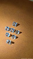 Seven square-cut pale blue aquamarines displayed on surface
