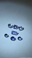 Seven faceted tanzanite stones arranged under direct light