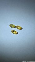 Three loose yellow oval gemstones on neutral background