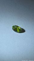 Top view of oval faceted vivid green peridot