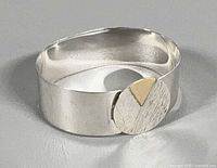 Top view of silver bracelet showing circular disc with gold inlay