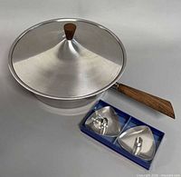 lidded pan with teak handle alongside boxed candlesticks