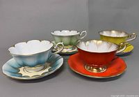 Four coloured Royal Albert teacup and saucer sets angled to show interiors and exteriors