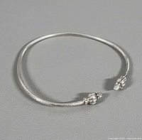 Full view of sterling silver open cuff bangle showing circular form and finial ends