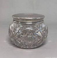 Front view of round cut glass jar with sterling lid