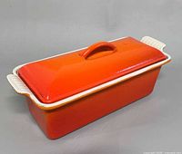 Rectangular casserole with lid in place showing orange exterior and side handles