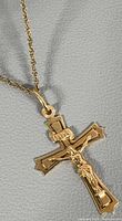 Close-up of crucifix pendant showing corpus figure, INRI banner, gold tone and bail attachment