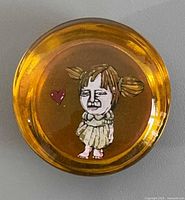 Top view of amber glass paperweight showing girl illustration and heart