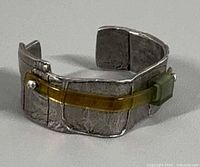 Front angled view showing textured metal surface, yellow resin strip and green cube accent