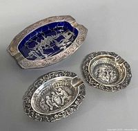 Three ashtrays: cobalt glass with silver overlay and two silver-plated ovals