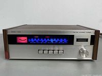 Front view powered on showing illuminated dial, controls and branding