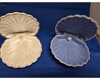 Two open clam shell trinket boxes, cream and blue, on blue background