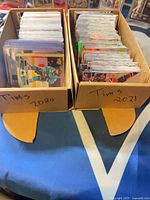 Two cardboard boxes labelled Tims 2020 and Tims 2021 filled with sleeved hockey cards