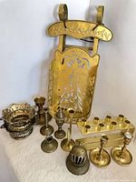 Group shot of all brass items including sleigh, candle block, bowl, bell, candlesticks