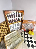 Group showing boxed plastic chessmen set, Kid Connection glass chess set, boards and foam insert
