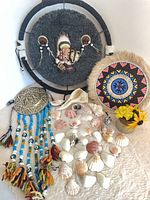 Overall lot showing both wall hangings, medallion with beads, shells, vase with flowers