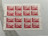Sixteen $1 red Canadian stamps arranged in four plate blocks with selvage showing printer imprint