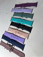 Top view of nine assorted Apple Watch silicone bands arranged in a row