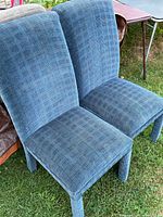 Front view of two blue cloth dining chairs outdoors on grass