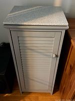 Full view of gray cabinet with marble top and louvered door