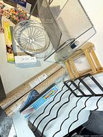 tabletop view showing wine rack, vinyl rolls, paint set, glass platter, mesh holder, power strip, parchment, wood stand, bottle