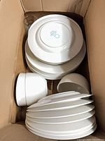Box with stacks of Martha Stewart white plates, bowls, one glass