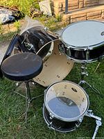Bass drum shell, tom, snare and throne grouped on grass