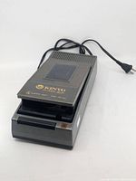Angled view of Kinyo UV-413 VHS rewinder showing lid, logo, power cord