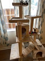 Full view of beige cat tree showing platforms, cubbies, ramp, and toys