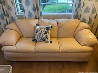 Front view of beige leather sofa with pillow arms