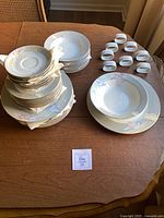 Full lot view showing stacks of three plate sizes, single soup bowl and napkin rings