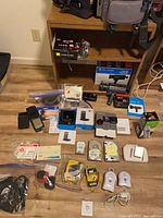 Group shot of cameras, PDA, Walkmans, hard drives, multimeters, cables on floor and shelf