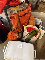 Pile of camping gear showing backpack, coolers, stuff sacks and pots