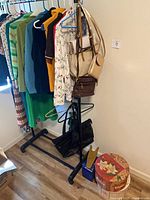 Full view of garment rack with hanging clothes, multiple handbags, hat box and tie rack on floor