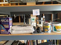 Shelf view showing EnviroTex box, two drop cloths, two trowels, Minwax can, adhesive tub